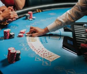 A dealer laying out cards on a casino table with chips and players watching