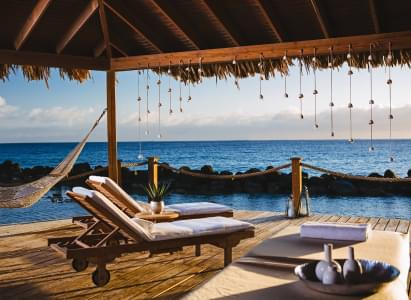 Two lounge chairs in a cabana overlooking the ocean