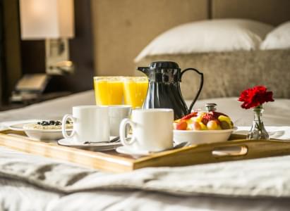 Breakfast in bed with fruit, coffee, and orange juice on a serving tray