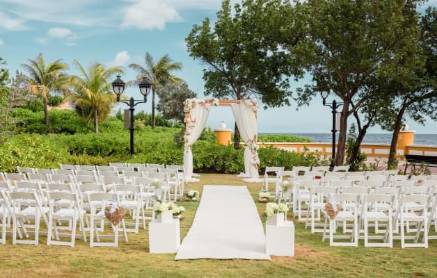 Small outdoor wedding ceremony with trees, empty white chairs, and flowers