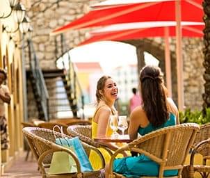 Two women sitting at an outdoor table under umbrellas