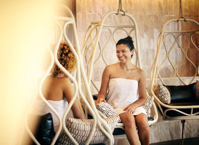 Two women in bathrobes sitting in the Wind Creek Chicago Southland spa